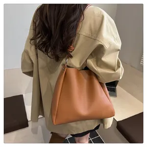 Detail of caramel tote bag showing side stitching and shoulder strap knot with silver metal ring
