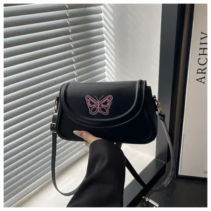 Detail of black crossbody bag with pink butterfly embroidery and gold metal buckle
