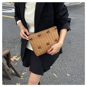 Dettaglio di una borsa trapuntata caramello con cuciture nere incrociate tenuta da una modella