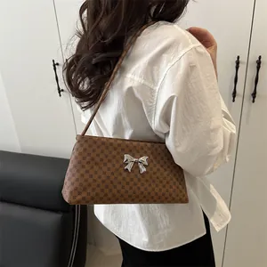 Brown monogram shoulder bag with silver butterfly buckle shown on model with white shirt