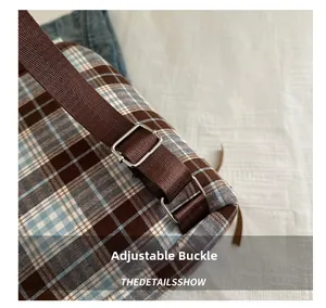Detailed macro view of an adjustable metal buckle and woven strap on a plaid backpack