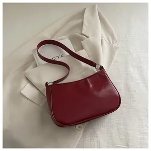 Detail of burgundy faux leather baguette bag with silver ring hardware and sleek texture