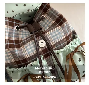 Detail of vintage plaid backpack showing silver magnetic buckle and drawstring closure