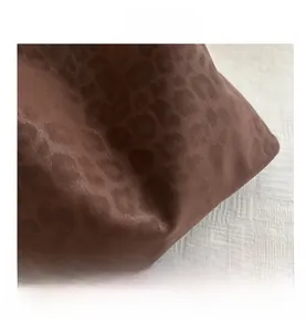 Vue détaillée du sac à main en cuir marron foncé avec motif léopard embossé et texte