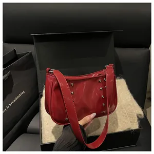 Detail view of red patent leather shoulder bag with metallic rivets in gift box setting