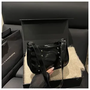Detail of glossy black leather shoulder bag featuring silver stud rivets on the surface