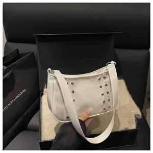 Detail of white patent leather shoulder bag featuring silver stud rivets and metal buckles