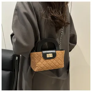 Detail of a brown quilted handbag with black leather handle and gold twist-lock closure