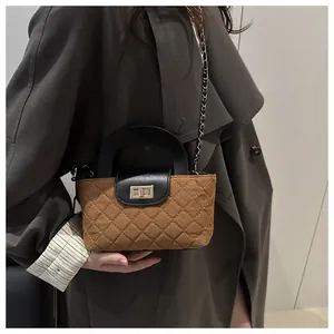Detail of brown quilted fabric crossbody bag with black leather flap and gold chain