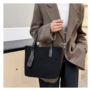 Dettaglio della borsa tote nera in pile con cinturino in pelle e targhetta moda