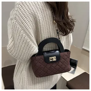 Detail of quilted brown fabric handbag featuring gold metal clasp and black handle