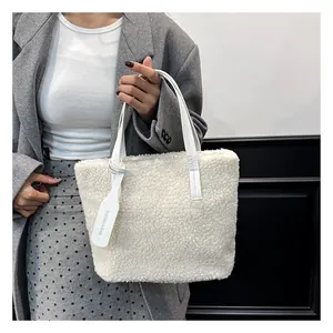 Dettaglio della consistenza in peluche bianco e della targhetta in pelle sulla borsa a secchiello