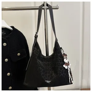 Détail du sac cabas léopard avec pendentif chien blanc et logo texte de mode