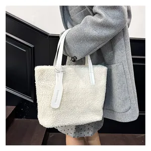 Dettaglio della borsa tote bianca in ecopelliccia con manici in pelle e ciondolo