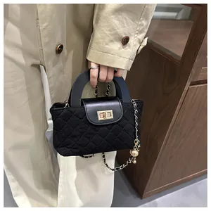 Close-up of quilted black handbag with gold twist lock and chic metal ball chain strap