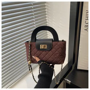 Detail of burgundy quilted velvet bag with gold lock and metal chain handle