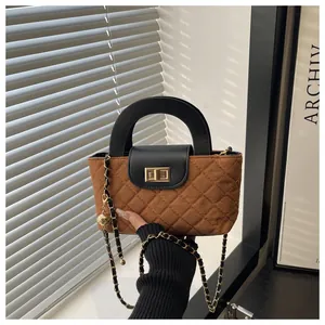 Close-up of brown quilted handbag with black leather flap and golden twist lock detail