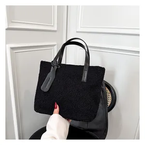 Dettaglio borsa tote nera in pelliccia sintetica con manico in pelle e ciondolo moda