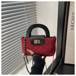 Detail of red quilted velvet bag with gold turn-lock and chain strap with gold ball charm