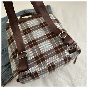 Detail view of the brown and blue plaid backpack with nylon straps and metal buckles