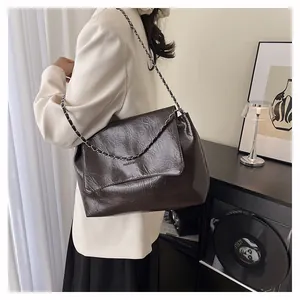 Detail of dark brown crinkle texture shoulder bag with chain strap and embossed text
