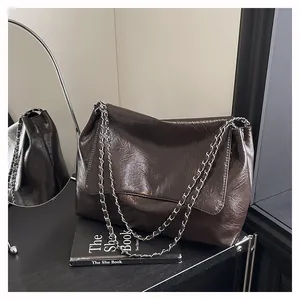Detail of dark brown crinkled leather shoulder bag with silver chain and logo