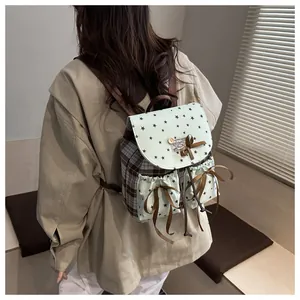 Detail view of vintage checkered backpack with green star print and lace bow accents