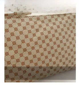 Dettaglio macro in pelle grana beige con motivo a monogramma cuore e cuciture