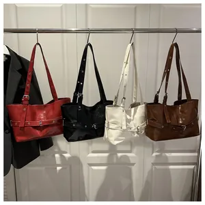 Detalle de cuatro bolsos tote de cuero en rojo, negro, blanco y marrón en una puerta