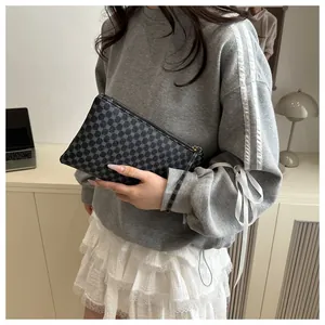 Dettaglio della pochette geometrica grigio scuro con cerniera e cinturino da polso