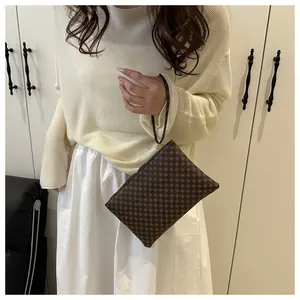 Portafoglio da polso marrone con stampa geometrica indossato da una modella