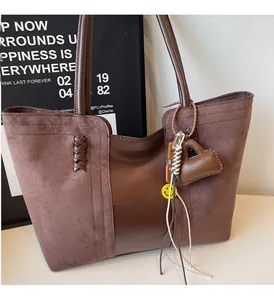 Dettaglio della borsa tote in pelle scamosciata marrone con decorazioni e ciondoli