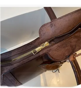 Dettaglio della cerniera in metallo dorato e della texture scamosciata marrone della borsa