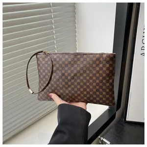 Dettaglio della pochette lunga marrone scuro con motivo vintage e cerniera dorata