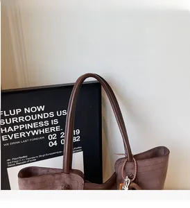 Dettaglio della borsa tote in pelle scamosciata marrone con cuciture rinforzate e manici