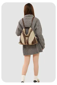 Detail of vintage canvas backpack with brown leather trim and golden metal rivet accents