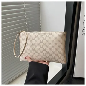 Dettaglio del portafoglio lungo monogramma beige con cerniera e cinturino da polso elegante