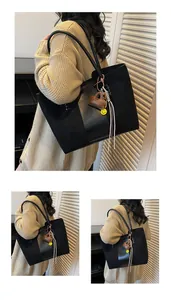 Dettaglio della grande borsa tote nera con trama scamosciata e ciondolo a forma di smile