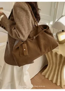 Detail of a large brown suede tote bag with a small coin purse and minimalist straps