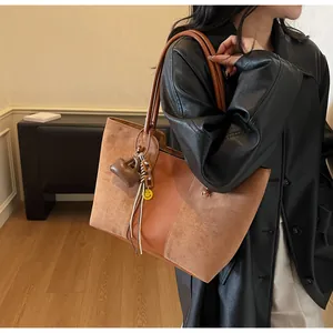 Dettaglio della borsa tote caramello con texture in pelle e ciondoli decorativi