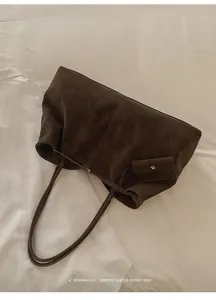 Detail of dark brown suede tote bag with matching pouch on minimalist white bedding