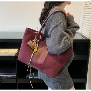 Dettaglio borsa tote in pelle scamosciata bordeaux con ciondolo mini e tag smiley giallo