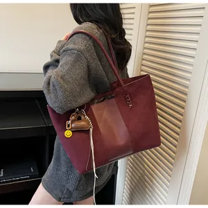 Dettaglio della borsa tote bordeaux con patchwork in pelle scamosciata e ciondolo