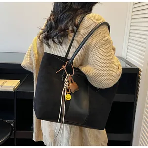 Dettaglio della grande borsa tote in pelle scamosciata nera con ciondolo smiley
