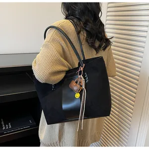 Dettaglio della grande borsa tote nera con ciondoli a forma di smile e nappe sulla spalla