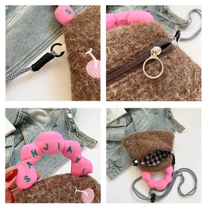 Dettaglio della borsa in peluche marrone con manico rosa e ricami di ciliegie fini