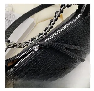 Detailansicht der schwarzen Krokodilprägung und der silbernen Kette der Handtasche