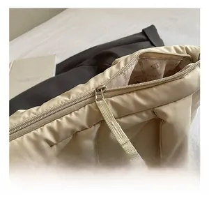 Close-up of the smooth metal zipper and branded lining of the beige quilted tote bag