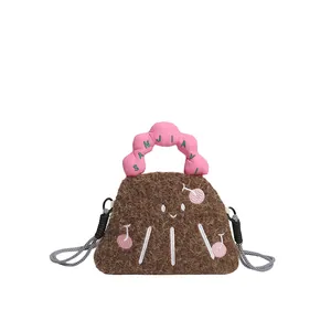 Dettaglio della borsa di peluche marrone con manico rosa ondulato e ricamo di ciliegie