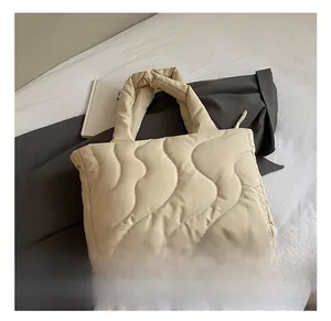 Close-up of quilted wave pattern and soft texture on a large cream puffer tote bag